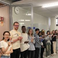 a group of college students lined up near the side wall of a modern looking hallway